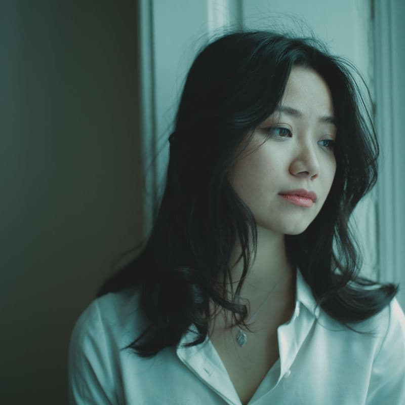 窓の外を見つめ、将来や働き方について考える20代後半の女性